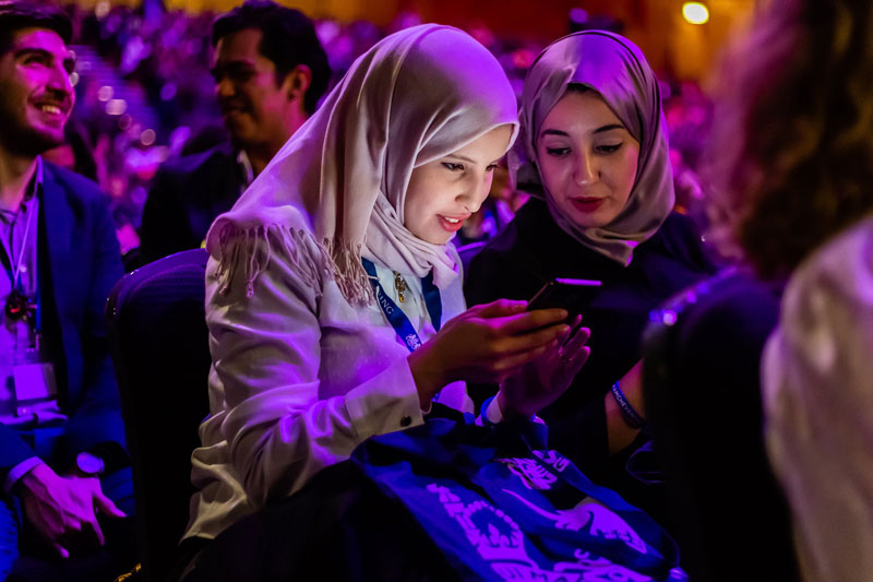 Scholar on phone during Orientation 2018