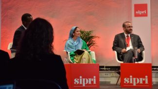 Heela sits on stage with another panel member.