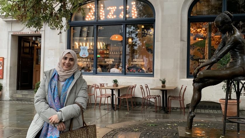 A woman leaning against a brick wall outside